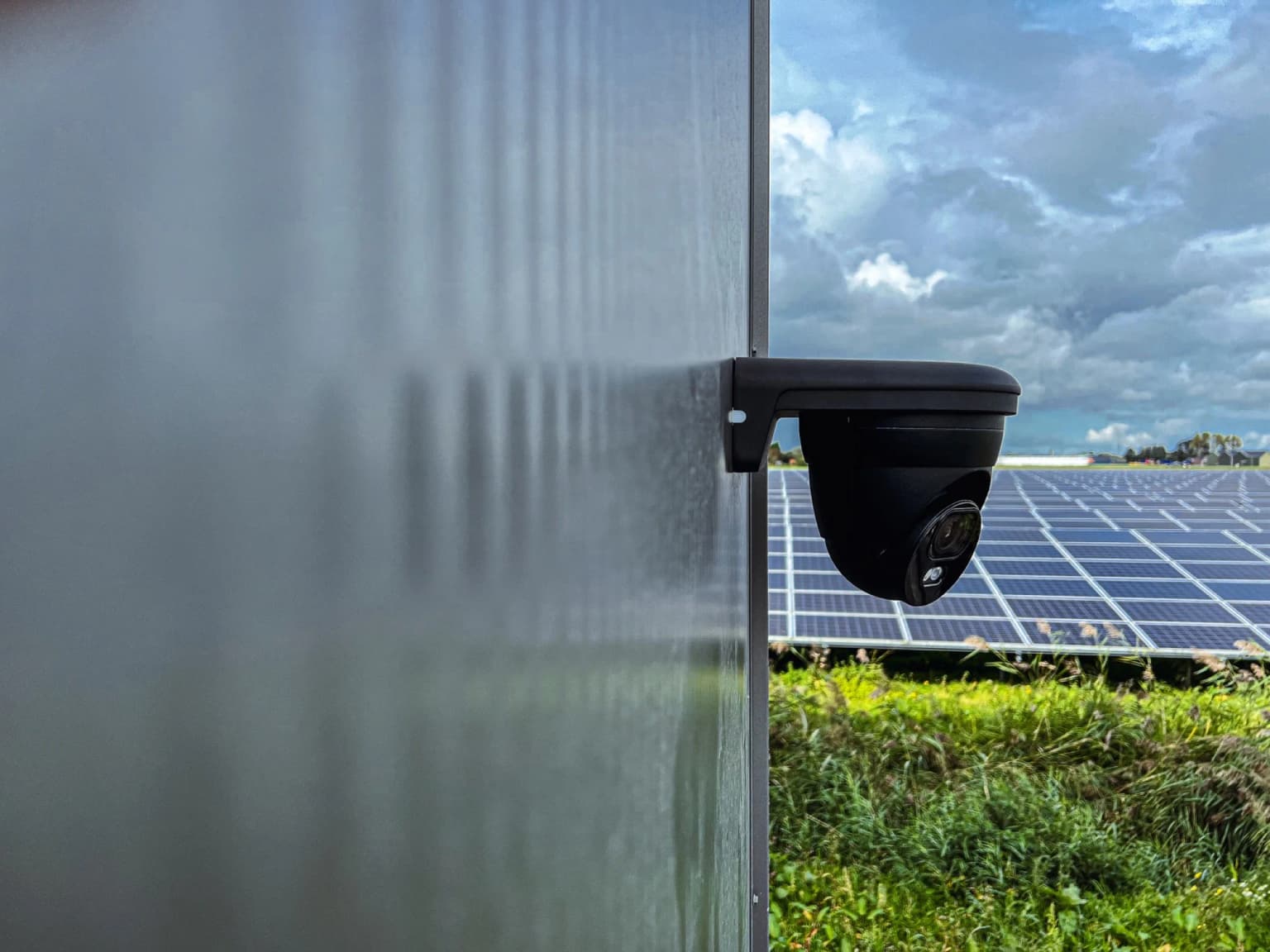 Buitencamera professioneel gemonteerd aan metalen gevel onder blauwe lucht