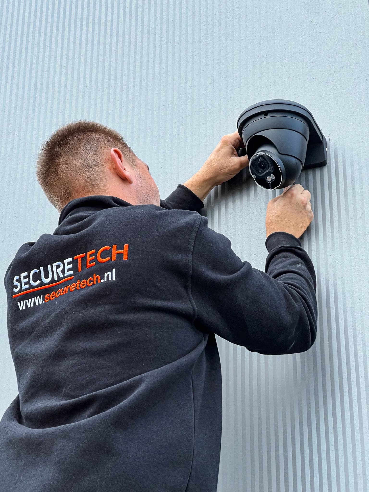 Securetech monteur plaatst beveiligingscamera in Securetech hoodie