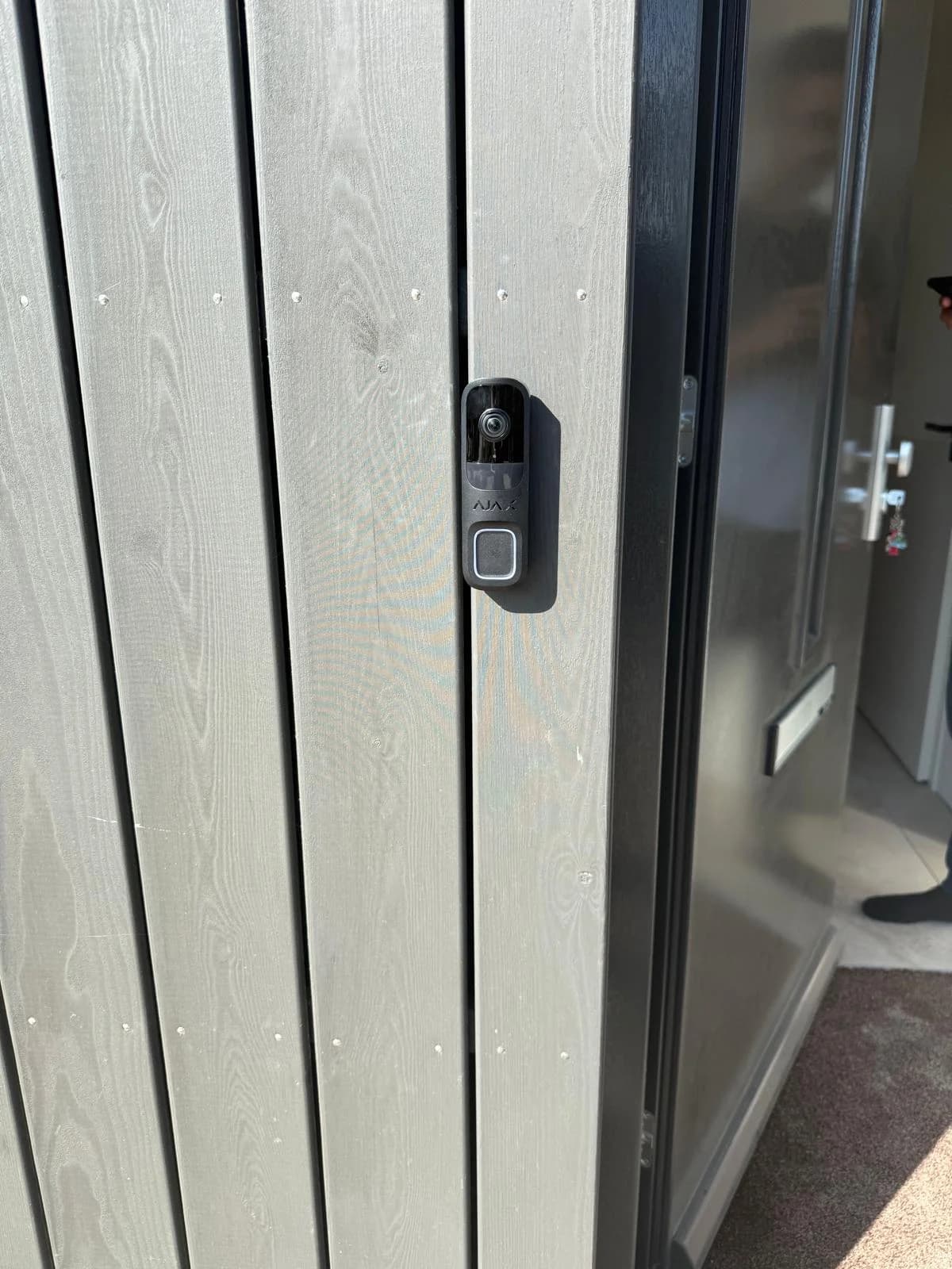 Ajax video-deurbel op grijze houten gevel van woning Almere, zij-aanzicht