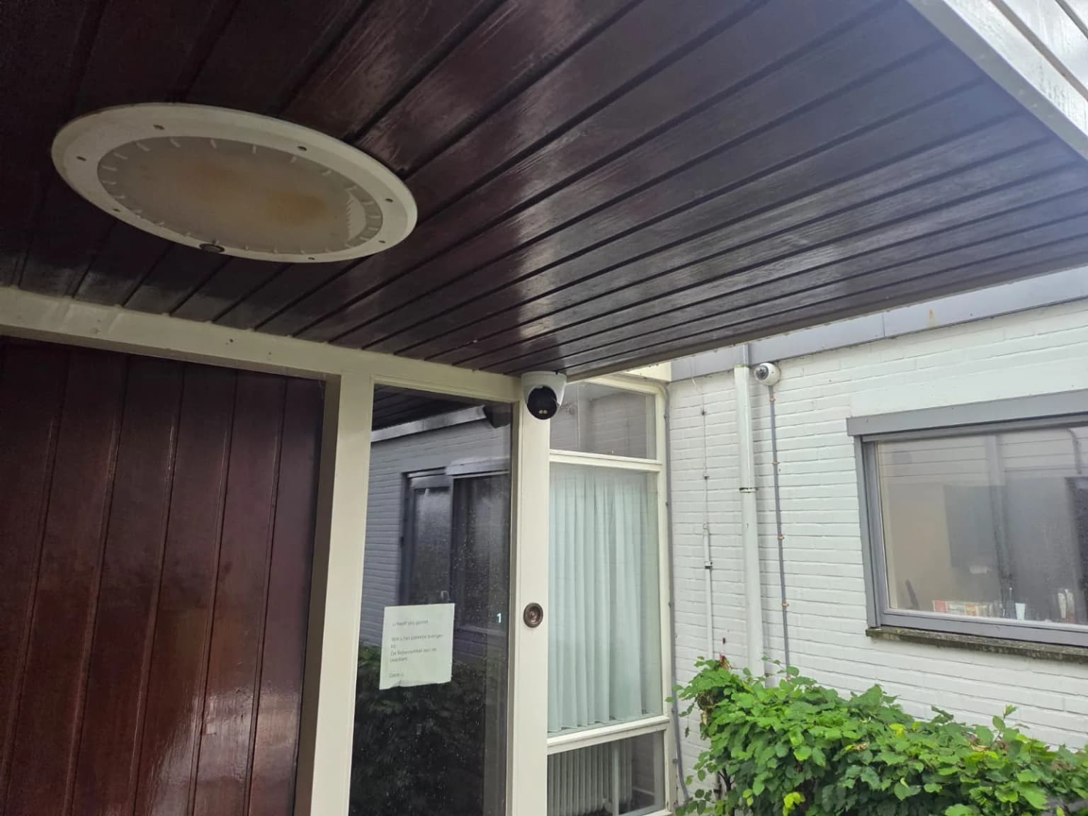 Dome bewakingscamera onder de luifel gericht op een toegangsdeur aan de achterzijde van de katholieke kerk in Wognum
