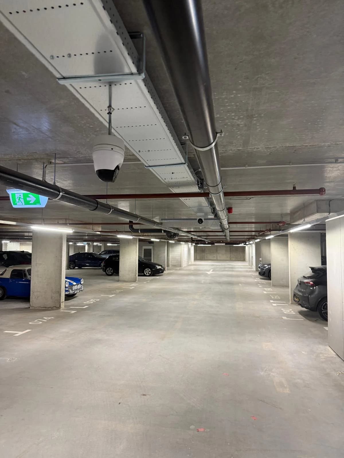 Dome camera bij nooduitgang-bord in parkeergarage VvE Nottinghill Hoofddorp