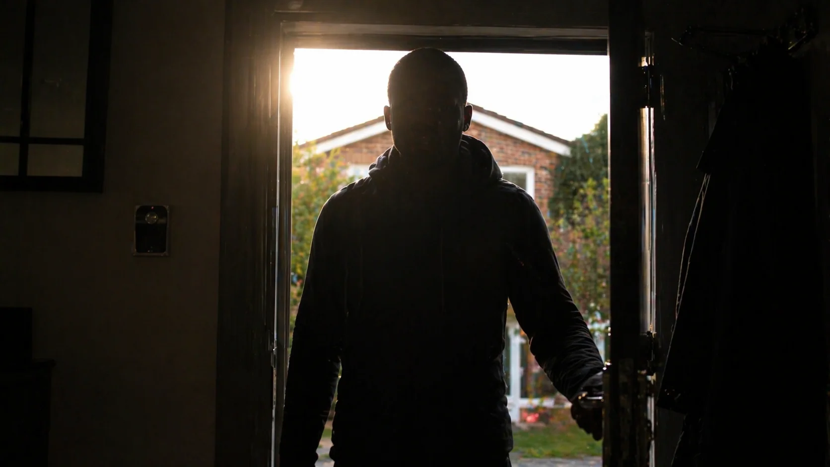 Persoon in silhouet bij deuropening met sterk tegenlicht van de zon, gezicht volledig in schaduw